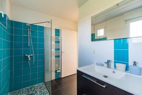 een badkamer met een wastafel en een douche met blauwe tegels bij La maison d'Alphonse : Plouha, proche de la plage in Plouha