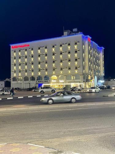 a car driving past a large building at night at سحاب الأندلس للأجنحة الفندقية - املج in Umm Lujj