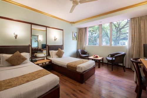 a hotel room with two beds and a television at Nahar Heritage Hotel in Bangalore