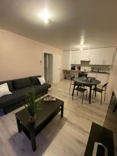 a living room with a couch and tables and a kitchen at Douce Escale in Strasbourg