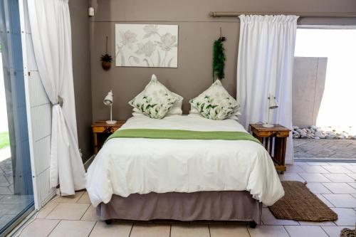 una camera da letto con un grande letto con lenzuola e cuscini bianchi di Nine on Uys street B & B a Jeffreys Bay