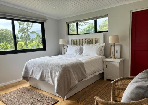 a bedroom with a large bed with two windows at Oakhurst Farm Cottages in Wilderness