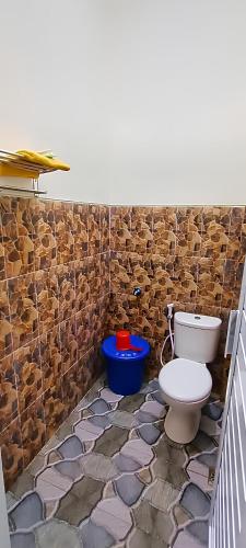 a bathroom with a toilet and a stone wall at Kinasih Homestay in Pacitan