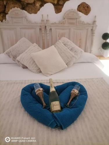 Una botella de vino en una manta azul en una cama en Almodovar alojamientos 1 en Almodóvar del Río