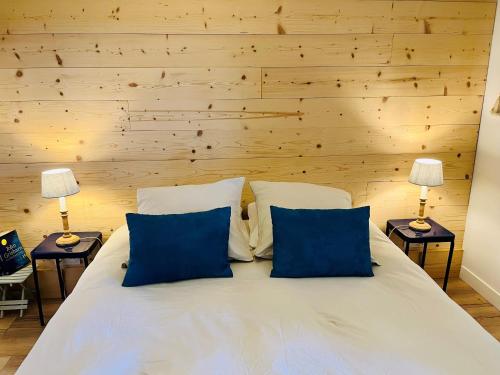 a bedroom with a large white bed with blue pillows at Le Credo in Collonges