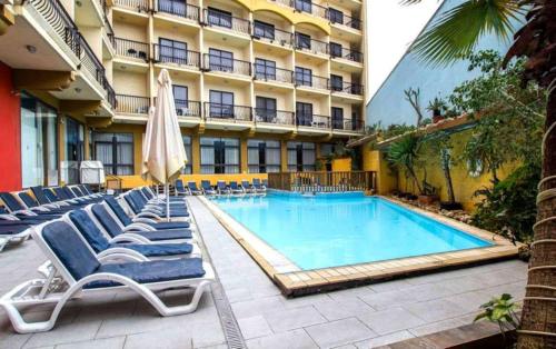 a swimming pool with lounge chairs and a hotel at Bella Vista Hotel in St Paul's Bay