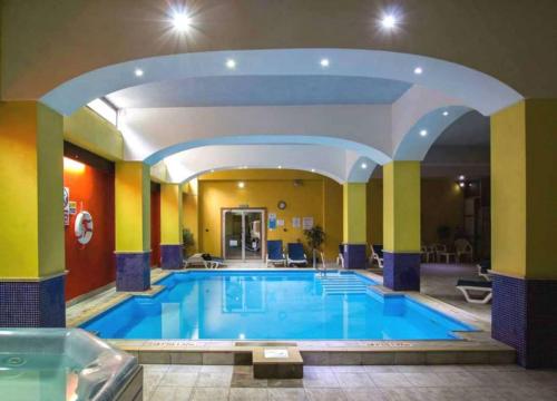 a large swimming pool in a hotel with an archway at Bella Vista Hotel in St Paul's Bay