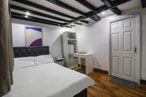 ein Schlafzimmer mit einem weißen Bett und einer weißen Tür in der Unterkunft OYO Tudor Oaks Lodge Stevenage North in Astwick