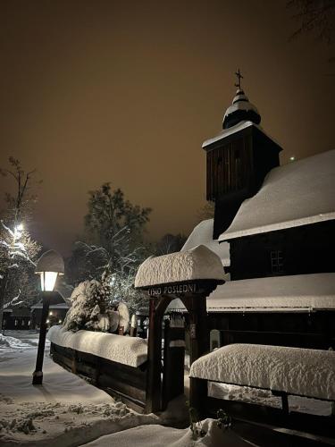a snow covered building with a clock tower and a street light at CHALUPA U ROUBÍČKŮ in Horní Bečva