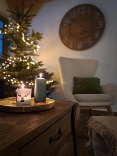 a candle on a wooden table next to a christmas tree at CHALUPA U ROUBÍČKŮ in Horní Bečva
