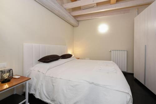 a bedroom with a white bed and a wooden table at Casa Margherita - new house in the ancient hamlet in Salò