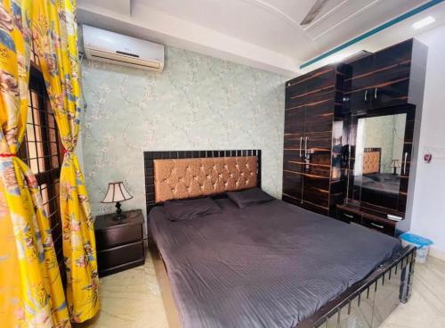 a bedroom with a large bed with a yellow curtain at Aquila Home 2 BHK South Delhi Near Ashram Metro in New Delhi