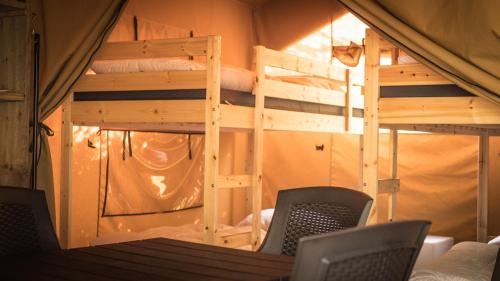 Pokój z 2 łóżkami piętrowymi, stołem i krzesłami w obiekcie Safari Tent XL Camping Belle-Vue w mieście Berdorf