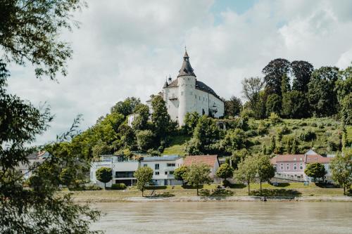 un castillo en la cima de una colina junto a un río en Privatzimmer - Sieben an der Donau en Ottensheim