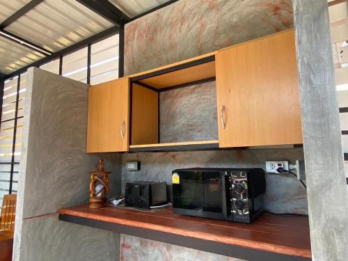 cocina con encimera, microondas y armarios en Suntalee House, en Nai Yang Beach