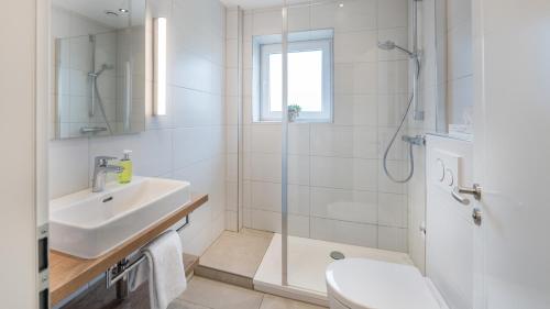 W łazience znajduje się prysznic, umywalka i toaleta. w obiekcie Landhotel Zur Eiche w mieście Buxtehude