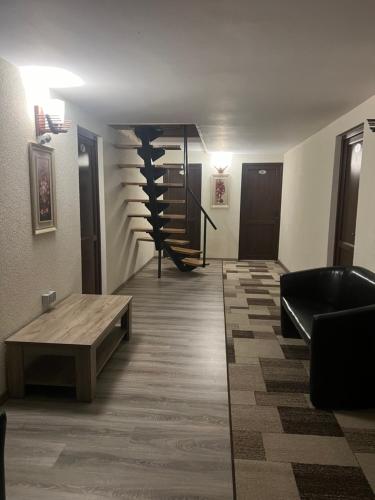 a room with a staircase and a couch and a table at Vila Casa cu Tei in Lupeni