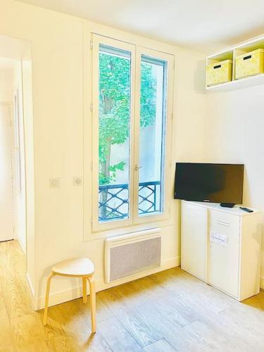 Cette chambre dispose d'une télévision, d'une chaise et d'une fenêtre. dans l'établissement In the center of Montmartre, à Paris