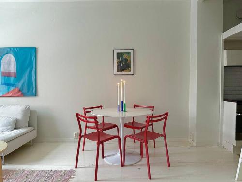 uma mesa com quatro cadeiras vermelhas e uma vela sobre ela em Cute loft by Tram Stop em Helsinque