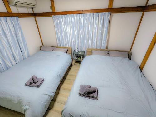 two twin beds in a room with windows at SquareHouse Nishiarai in Tokyo