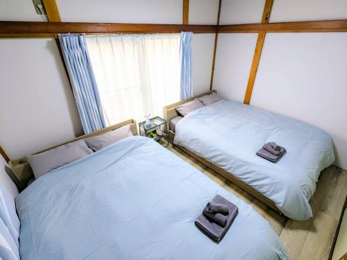 two twin beds in a room with a window at SquareHouse Nishiarai in Tokyo