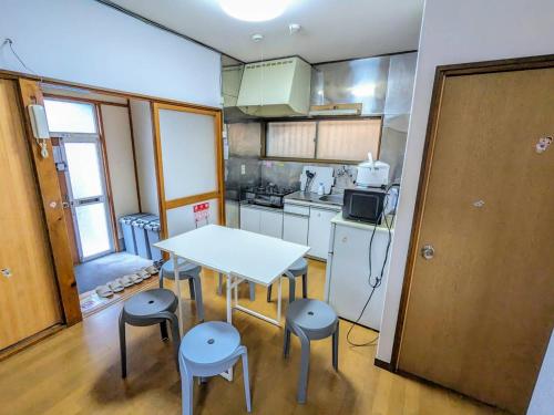 a small kitchen with a white table and stools at SquareHouse Nishiarai in Tokyo