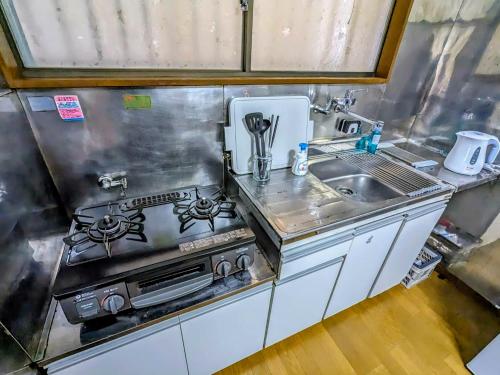 a kitchen with a stove and a sink at SquareHouse Nishiarai in Tokyo