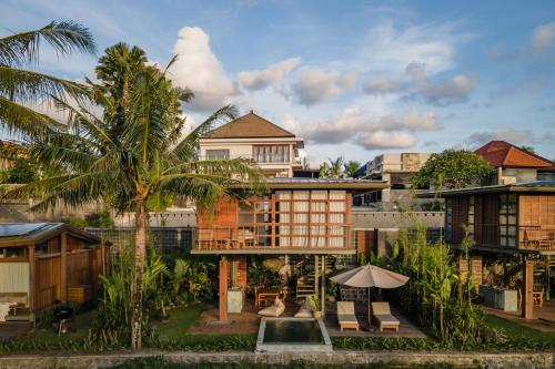 a resort with a building and a palm tree at Grün Canggu Garden in Canggu
