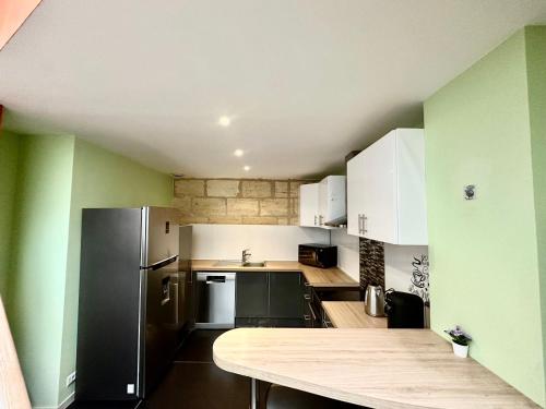 a kitchen with green walls and a black refrigerator at Maison Stylée 98m2 centre bordeaux in Bordeaux