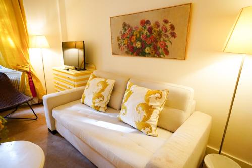 a living room with a white couch with pillows at Villa Escudier Appart-hôtel in Boulogne-Billancourt