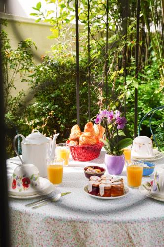 a table with breakfast food and orange juice on it at Villa Escudier Appart-hôtel in Boulogne-Billancourt