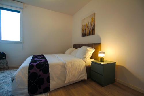 a bedroom with a bed and a lamp on a night stand at Skyview Luxury appartement à Montevrain in Montévrain