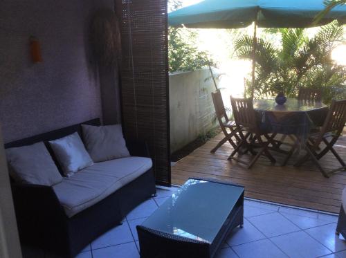 salon z kanapą, stołem i parasolem w obiekcie Deluy w mieście La Saline les Bains