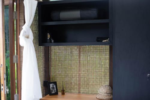 a black cabinet with a white curtain and a window at Calidas Hill in Kintamani