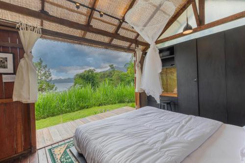 a bedroom with a bed and a large window at Calidas Hill in Kintamani
