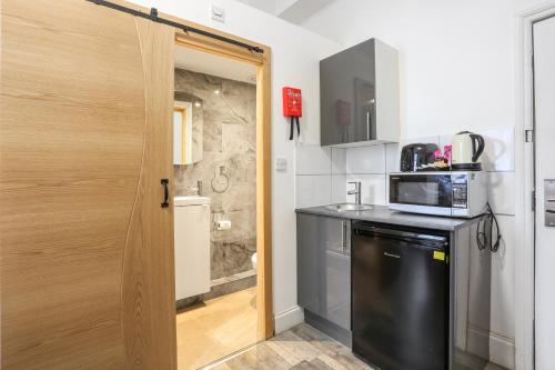 a kitchen with a black refrigerator and a microwave at BeiRoom Hyde Park Apartments in London