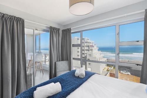 a bedroom with a bed and a view of the ocean at Ocean View 503 in Bloubergstrand