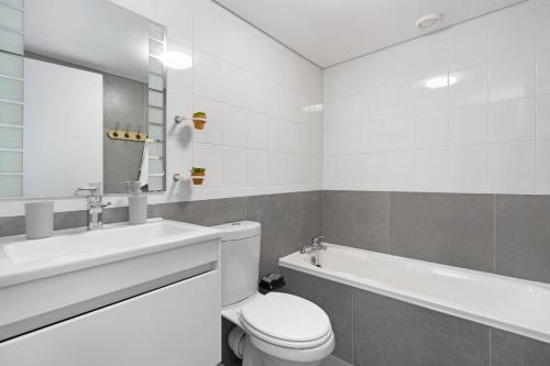 a bathroom with a toilet and a sink and a tub at Ocean View 503 in Bloubergstrand