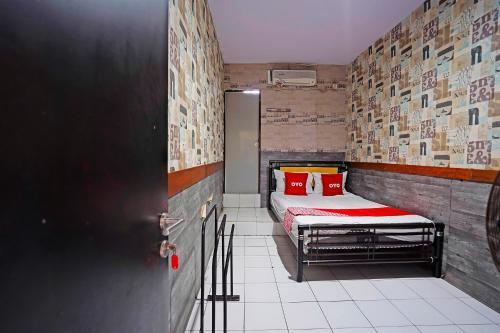 a small room with a bed with red pillows at OYO 91415 De Wijaya Hotel in Bungurasih