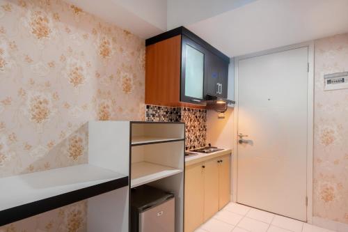 a small kitchen with brown cabinets and a white refrigerator at OYO Life 2837 Apartment Dramaga Tower in Bogor