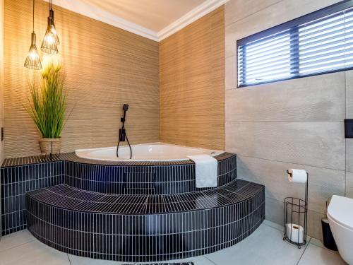 a bathroom with a tub and a toilet and a sink at One on Chelsea by Host Agents in Durban