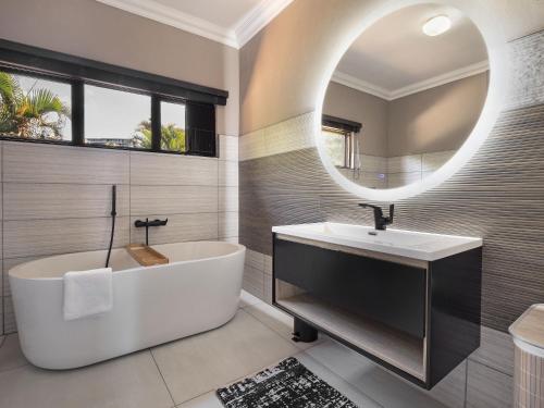a bathroom with a tub and a sink and a mirror at One on Chelsea by Host Agents in Durban