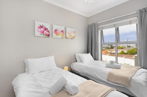 two beds in a room with a window at Nirvana 12 in Bloubergstrand