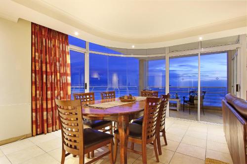 a dining room with a table and chairs and a large window at Ocean View C602 by HostAgents in Bloubergstrand