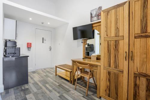 a room with a desk with a television and a door at BeiRoom Hyde Park Apartments in London
