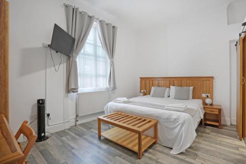 a bedroom with a bed and a tv and a table at BeiRoom Hyde Park Apartments in London