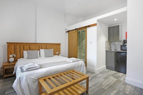 a bedroom with a large white bed and a kitchen at BeiRoom Hyde Park Apartments in London