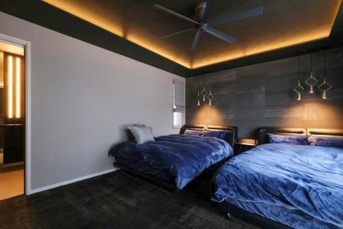 a bedroom with two beds and a ceiling fan at 暖炉の温もりとBBQが楽しめる高級ヴィラ【taizen】 in Fujikawaguchiko