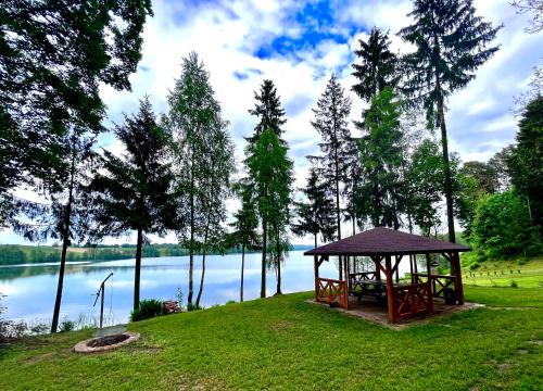 a gazebo in the grass next to a lake at Dom w Supieniach 