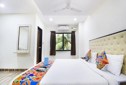 a bedroom with a large white bed and a window at Aravind Residency Calangute in Goa